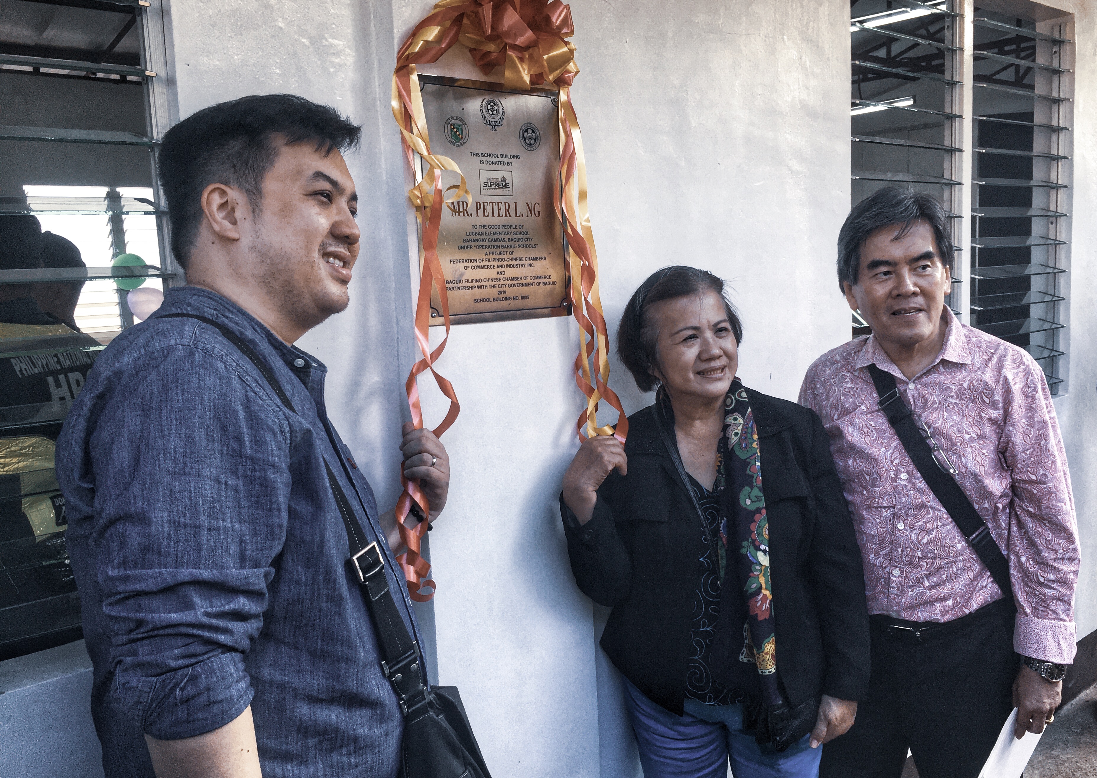 Hotel Supreme General Manager Jeff Ng with Hotel Supreme President Peter Ng and wife Ivy posing in front of the newly-donated classroom marker for Lucban Elementary School