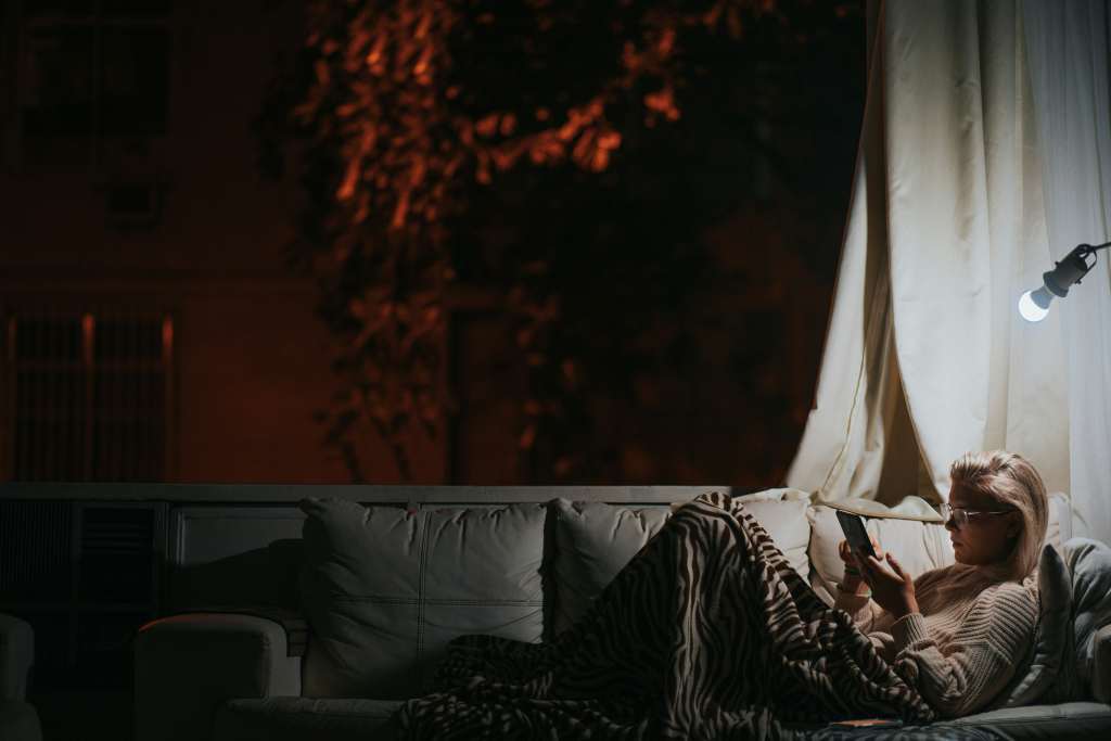 Woman sitting on her couch reading an e-reader at nigh